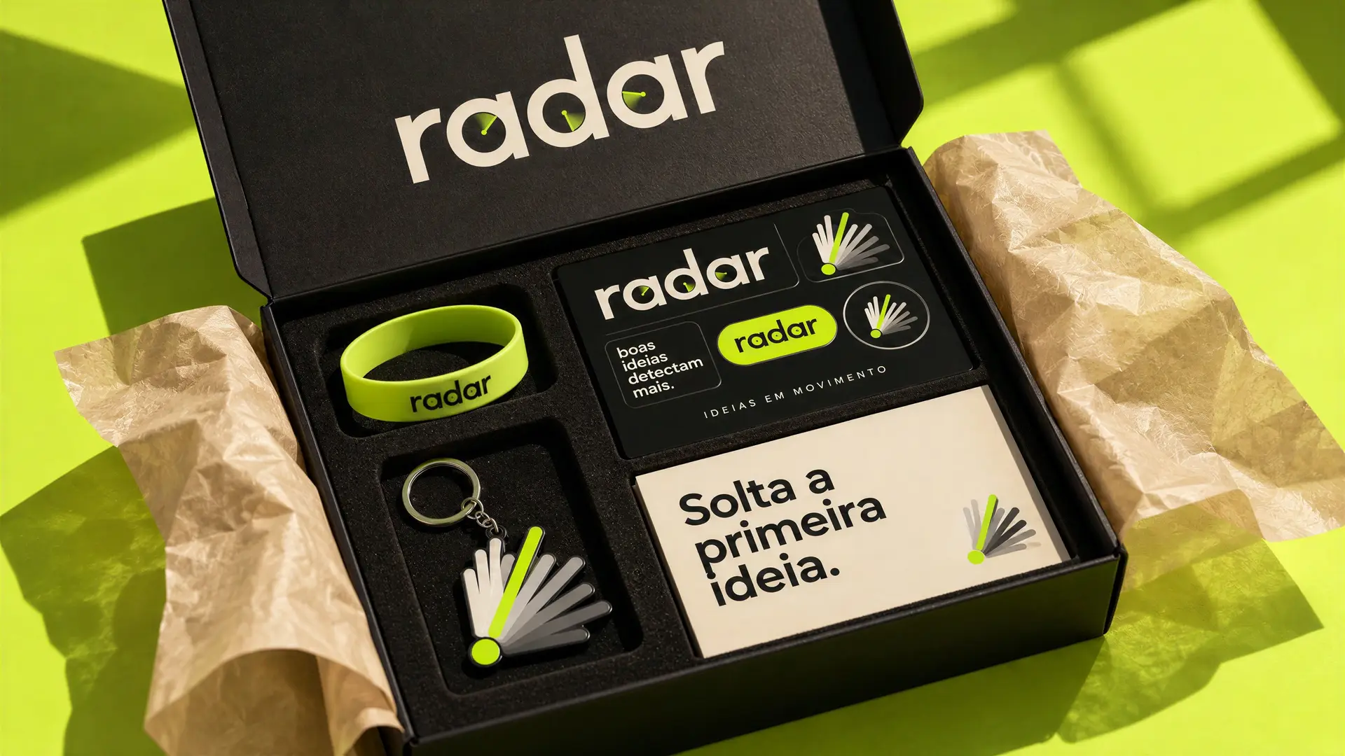 Caixa de boas-vindas do Radar aberta, com pulseira, chaveiro e cartões em verde fósforo