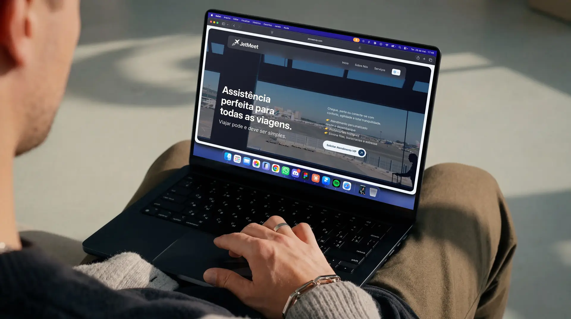 Pessoa com um notebook no colo, aberto no site da JetMeet, com o título “Assistência perfeita para todas as viagens.”