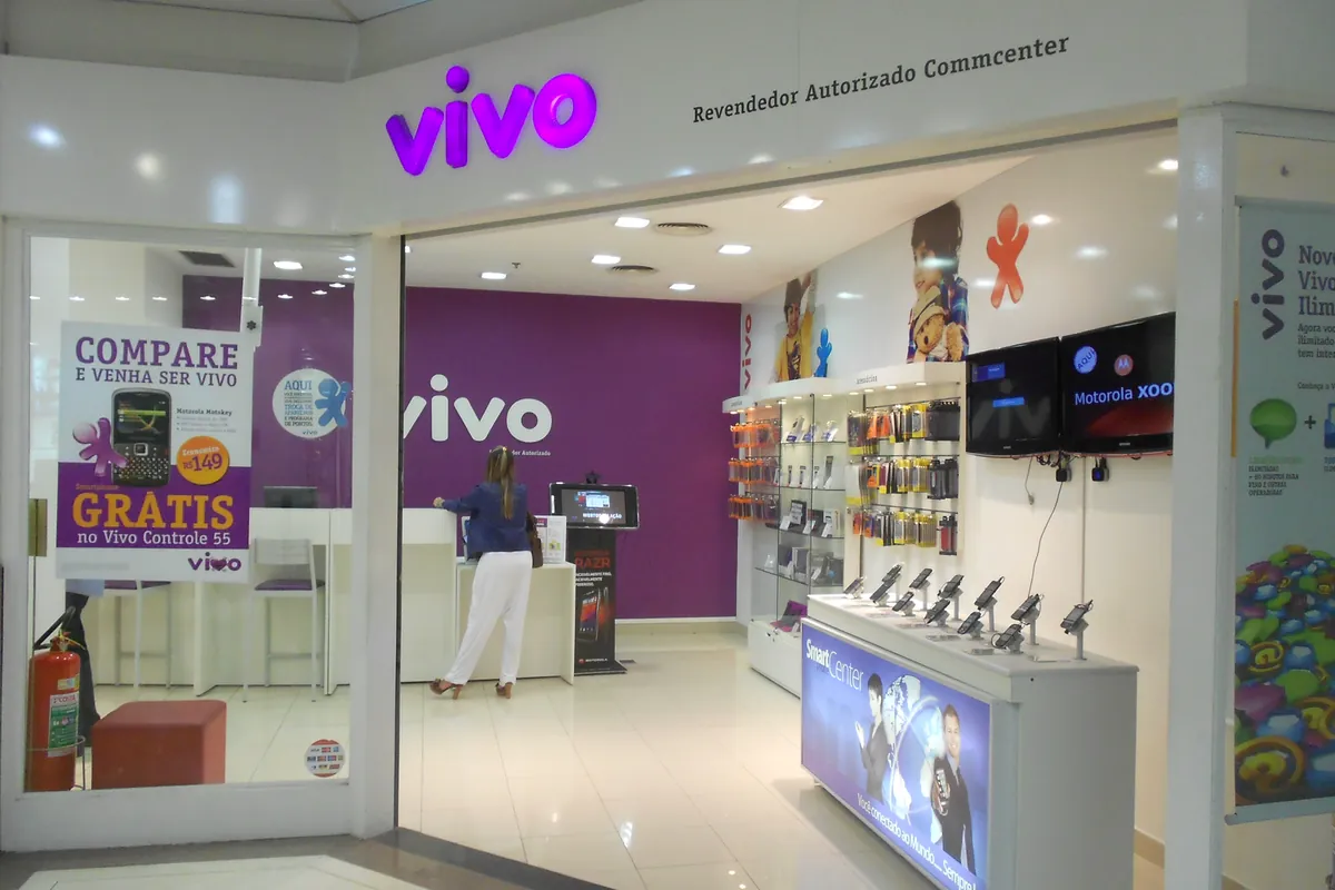 Fachada de uma loja da Vivo num shopping, com o nome roxo iluminado em cima da porta